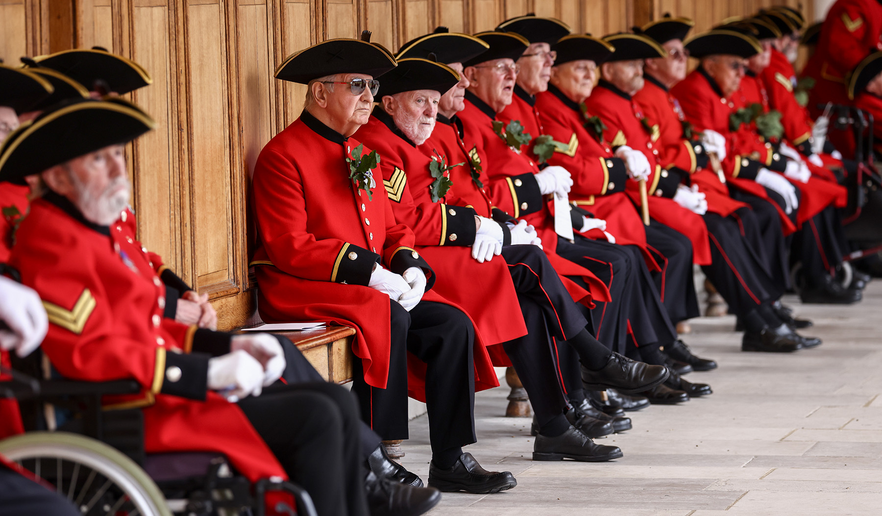 Chelsea Pensioners sitting along the colonnade in Figure Court during Founder's Day 2022.