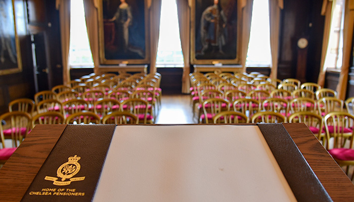 A lectern with a Royal Hospital Chelsea branded blotting pad overlooks rows of chairs for a corporate event