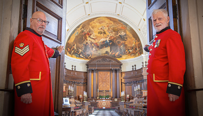 Chelsea Pensioners holding open the doors of the Wren Chapel to welcoming visitors