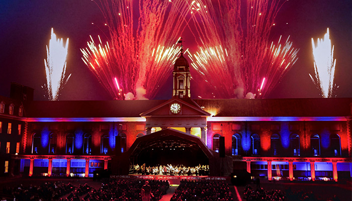 Spectacular fireworks exploding in the night sky over The Royal Hospital Chelsea as a live concert takes place on a stage in Figure Court.