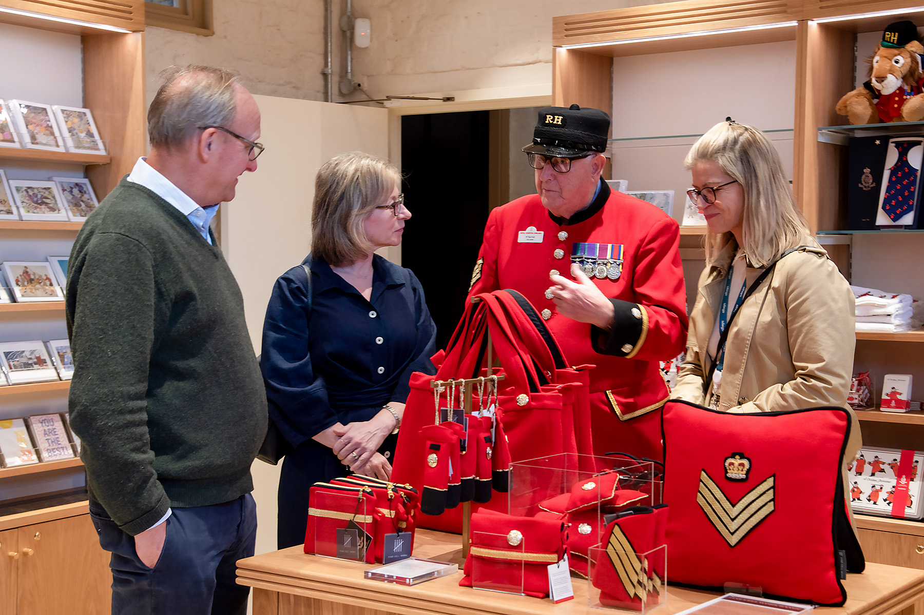 A Chelsea Pensioner stands with visitors inside the new post office & gift shop at the Soane Stable Yard