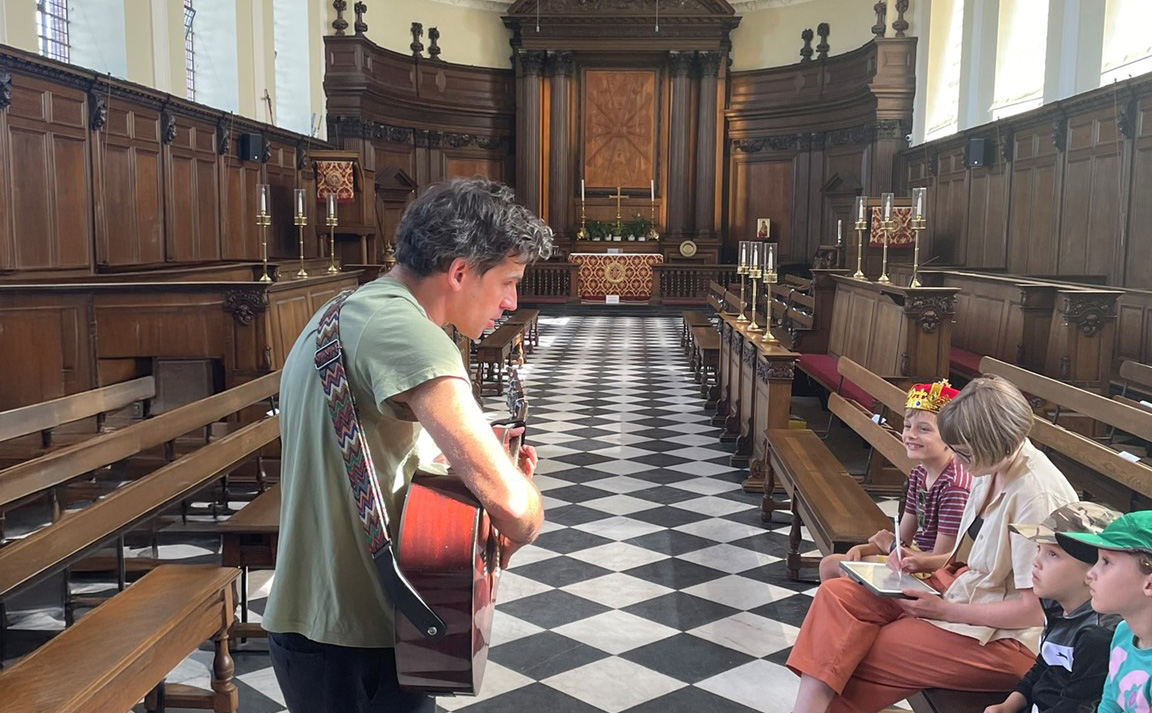 A musician plays his guitar for a family audience in the Wren Chapel at the Royal Hospital Chelsea