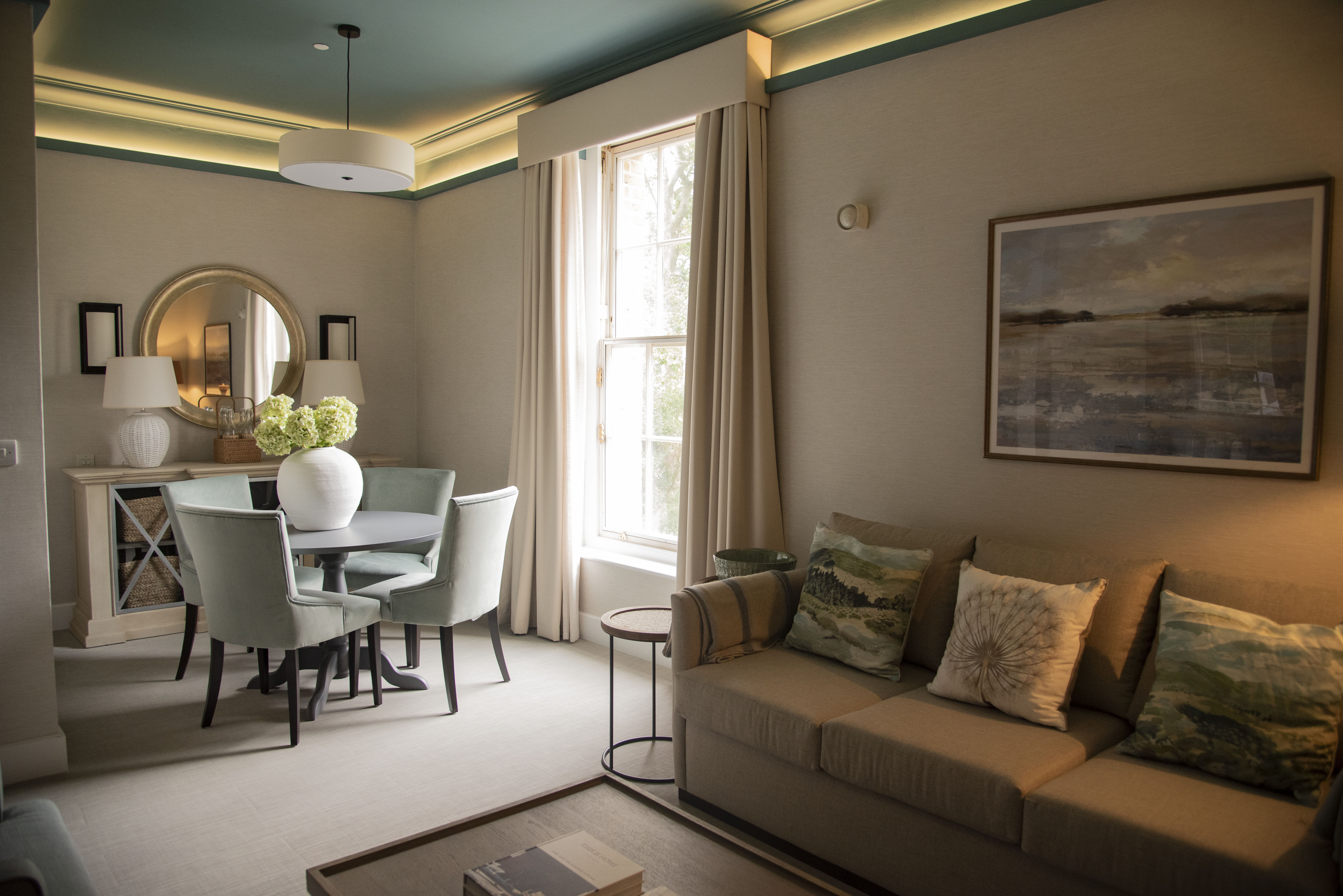 Room with sofa and table and chairs with large window in Infirmary building