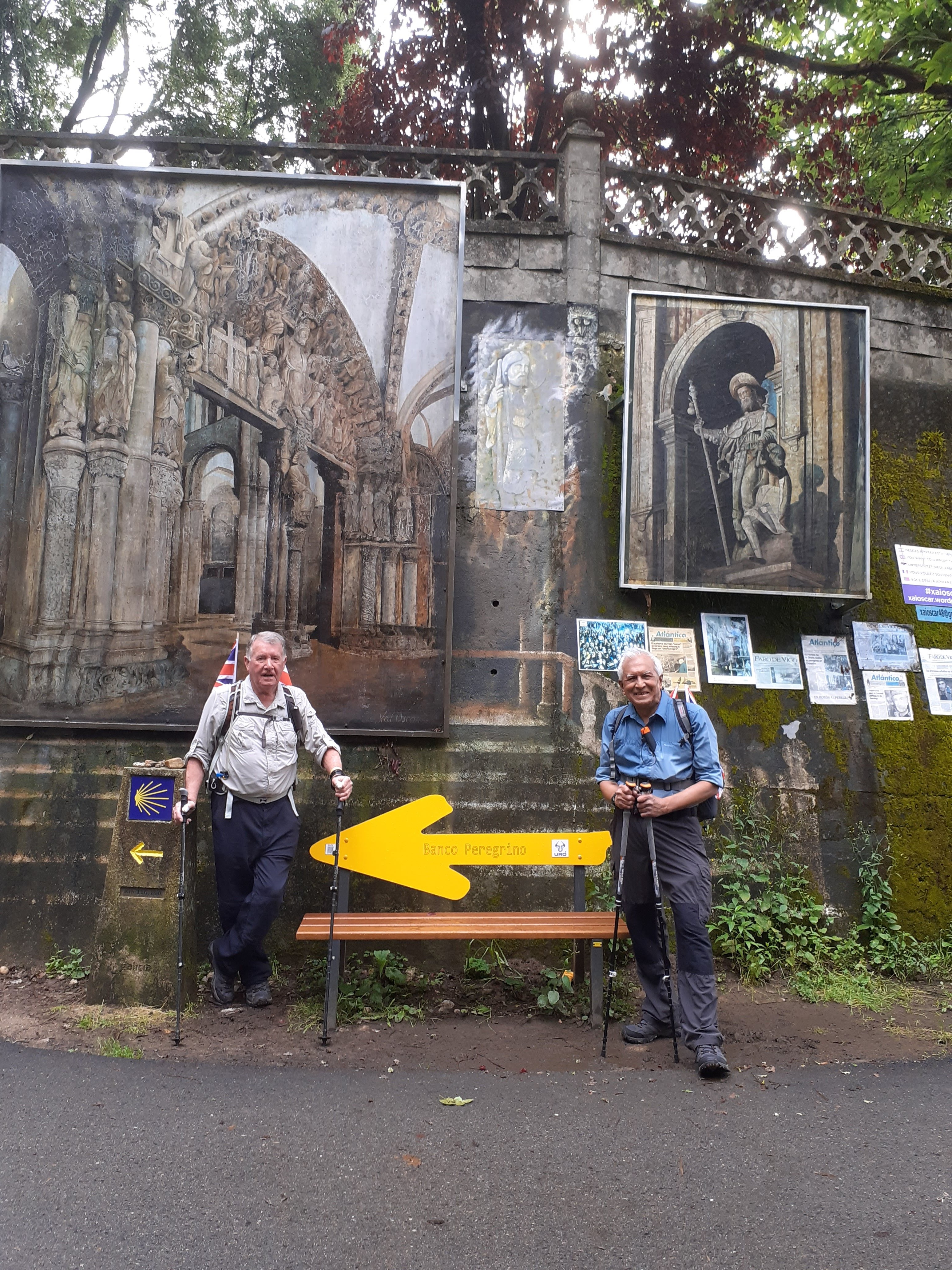 Two men in hiking gear stood in front of a bench