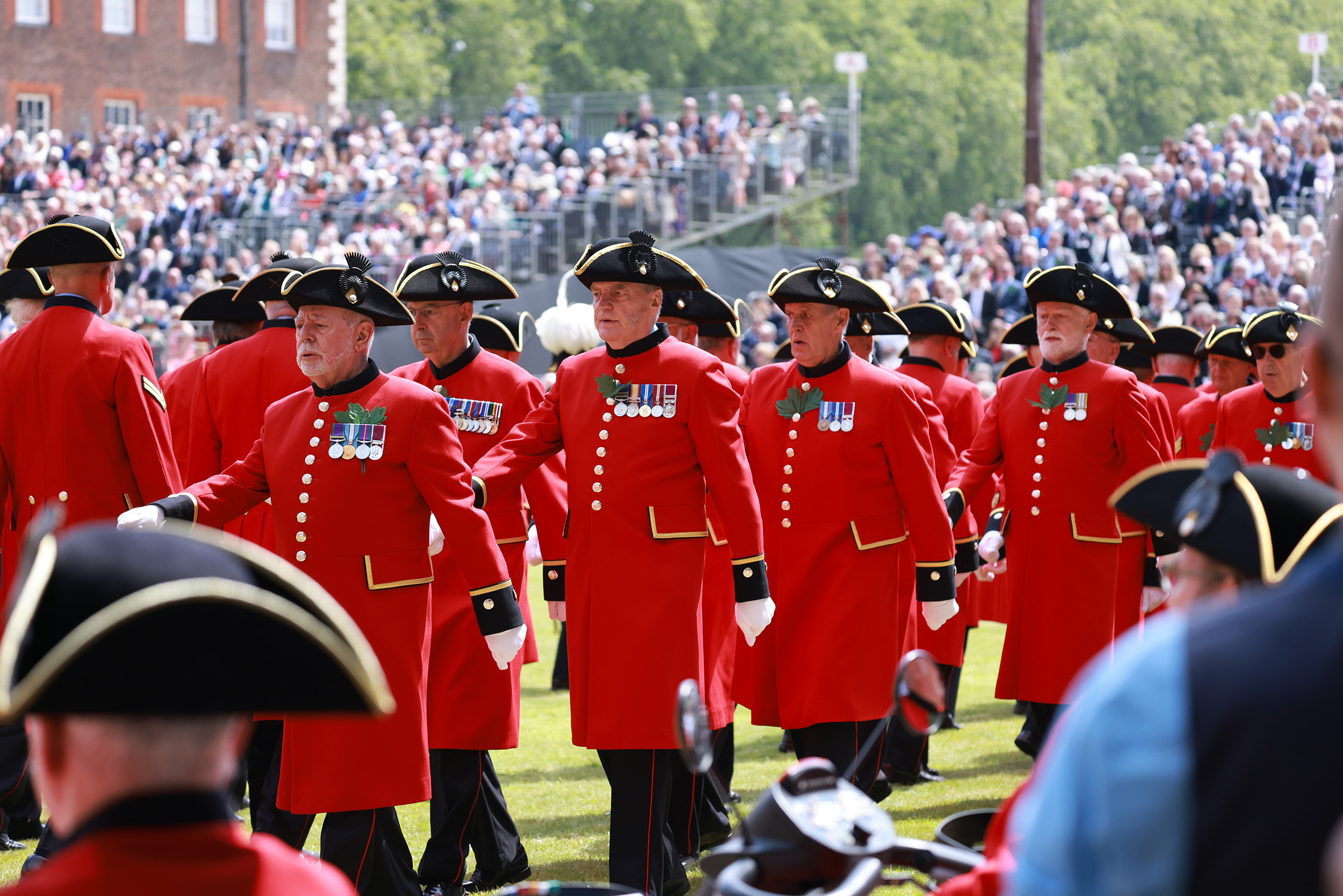 A group of Chelsea Pensioners march past an onlooking crowd on a bright day during Founders Day 2024