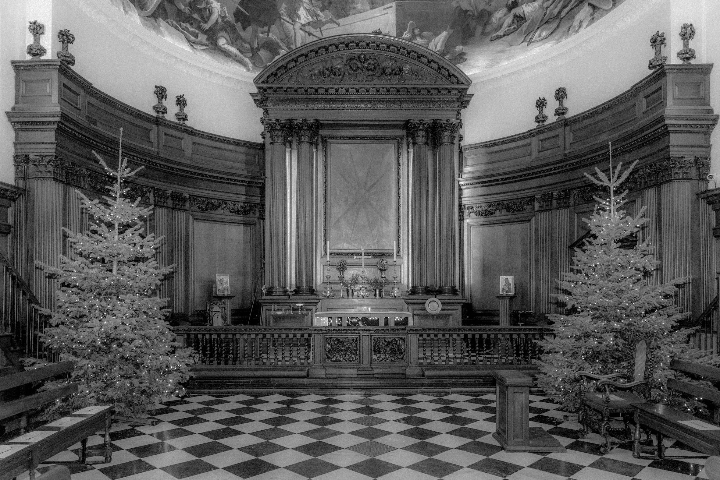 An old black and white photo of the alter at the Royal Hospital Chelsea's Wren Chapel - with Christmas trees on either side of the photo