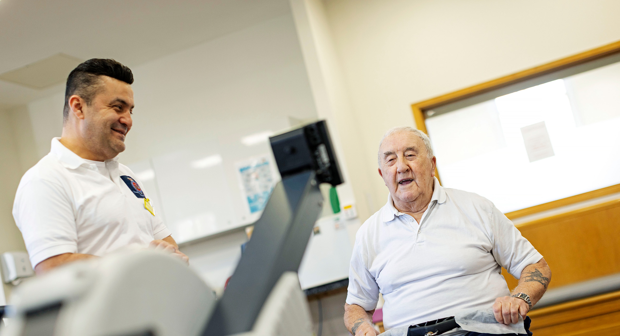A fitness instructor supports a veteran in using a seated rowing machine.