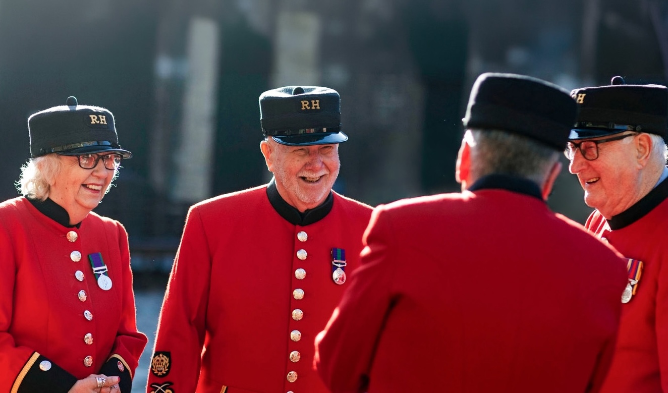 Chelsea Pensioners, dressed in iconic scarlet uniform, gather in the Soane Stable Yard laughing together