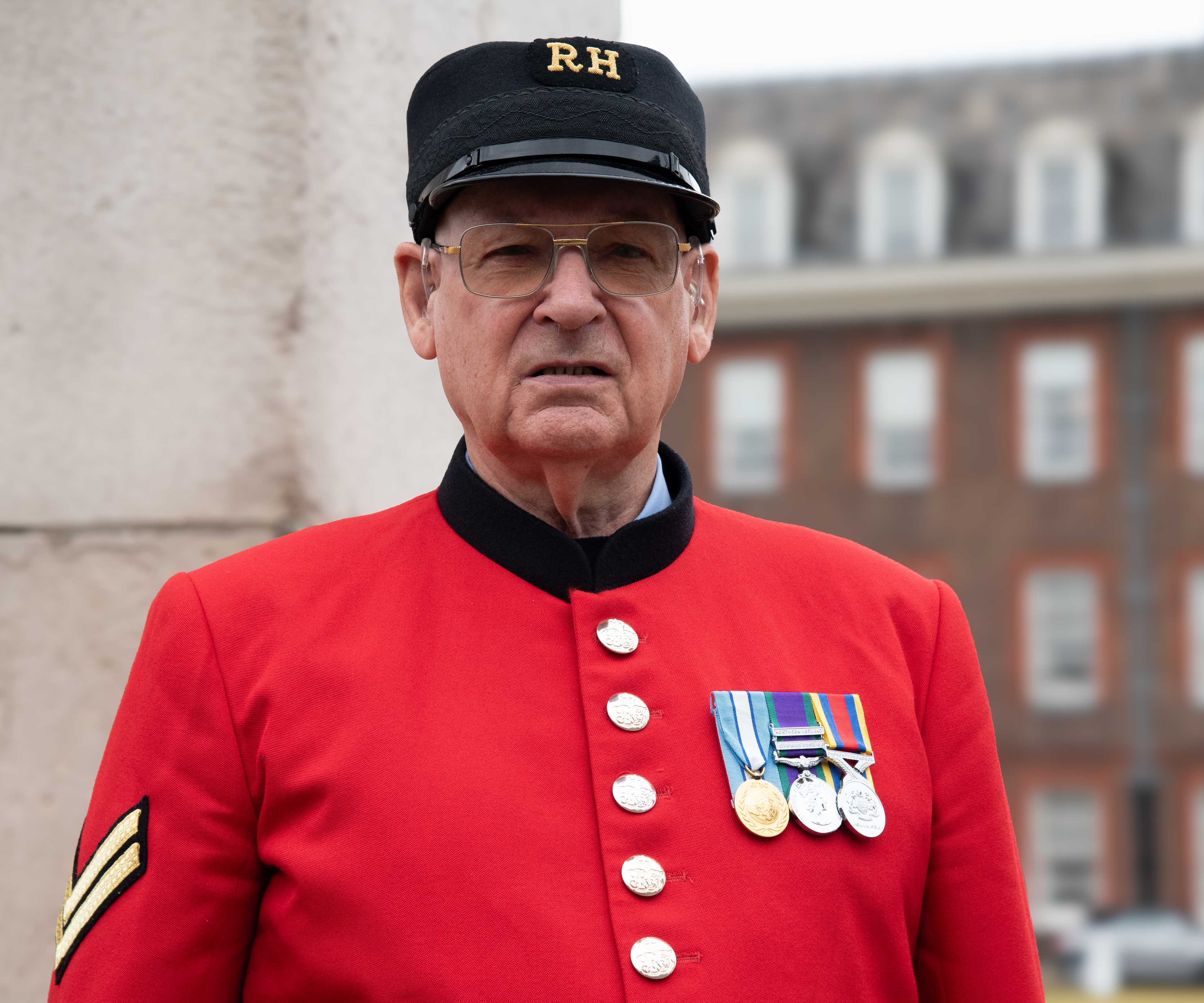 Chelsea Pensioner in scarlets and shako looks at the camera