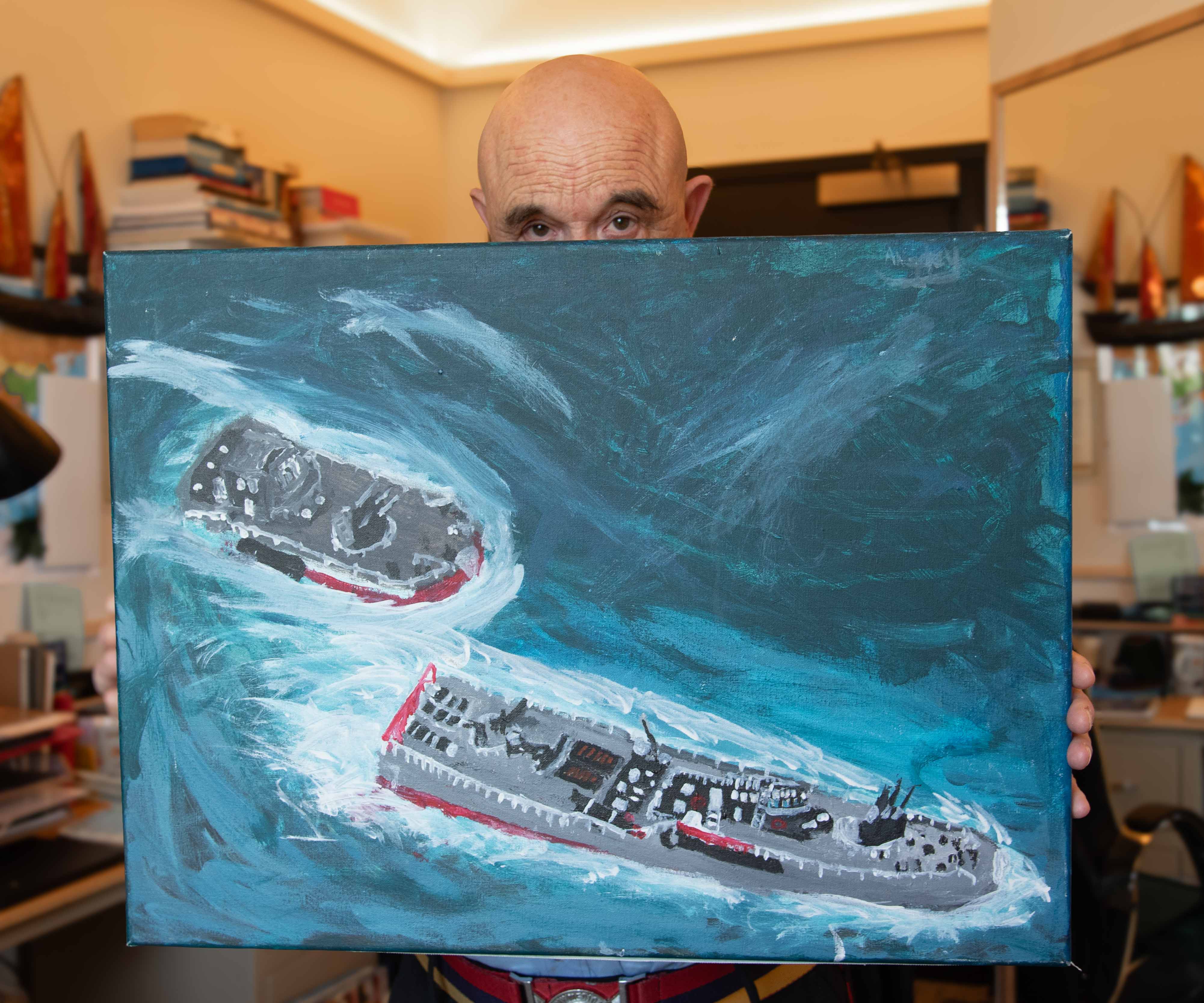 Chelsea Pensioner, Tony, holds a large canvas he has painted of two Navy battleships at sea