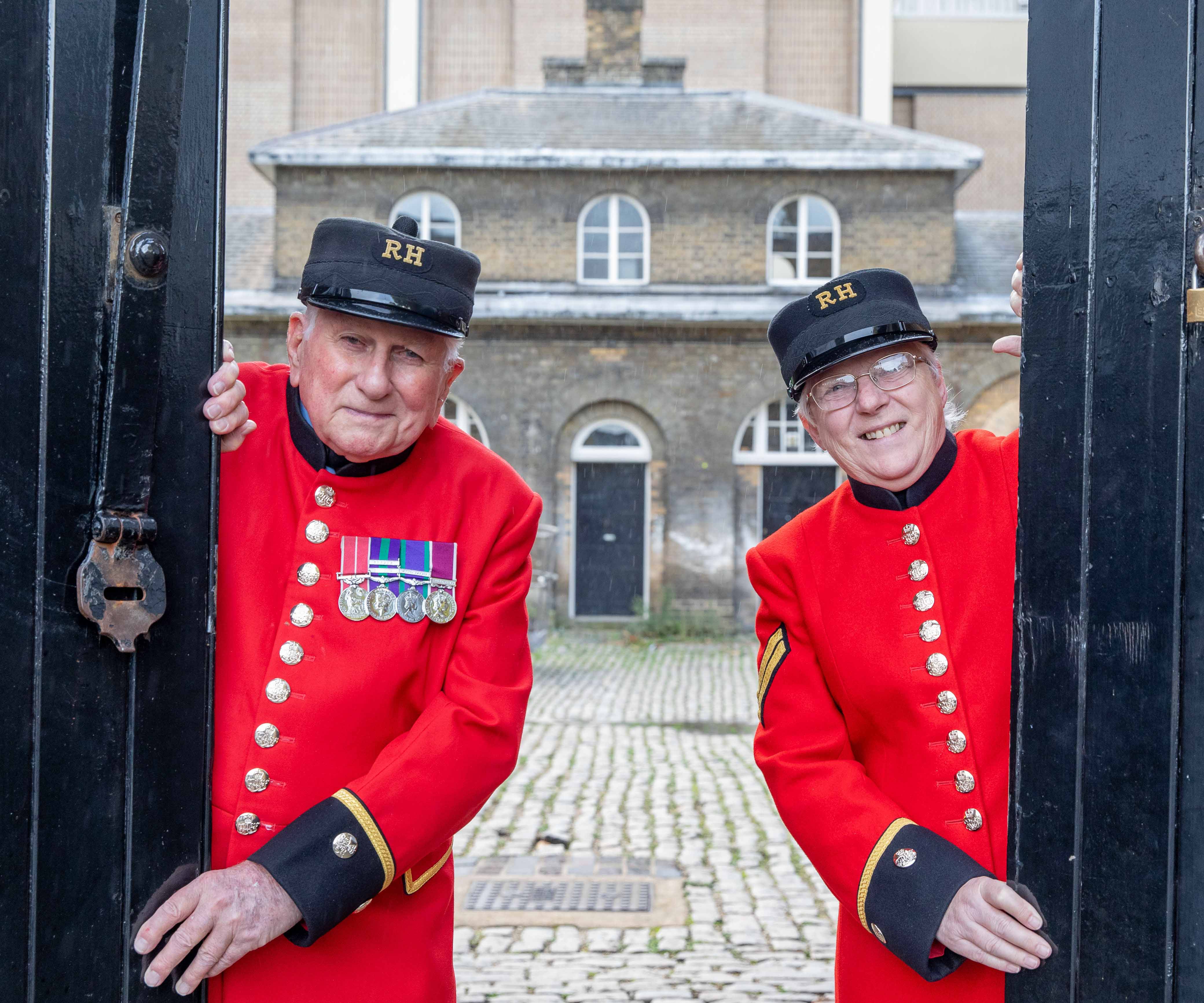 Two Chelsea Pensioners opening the gate to the Soane Stable Yard