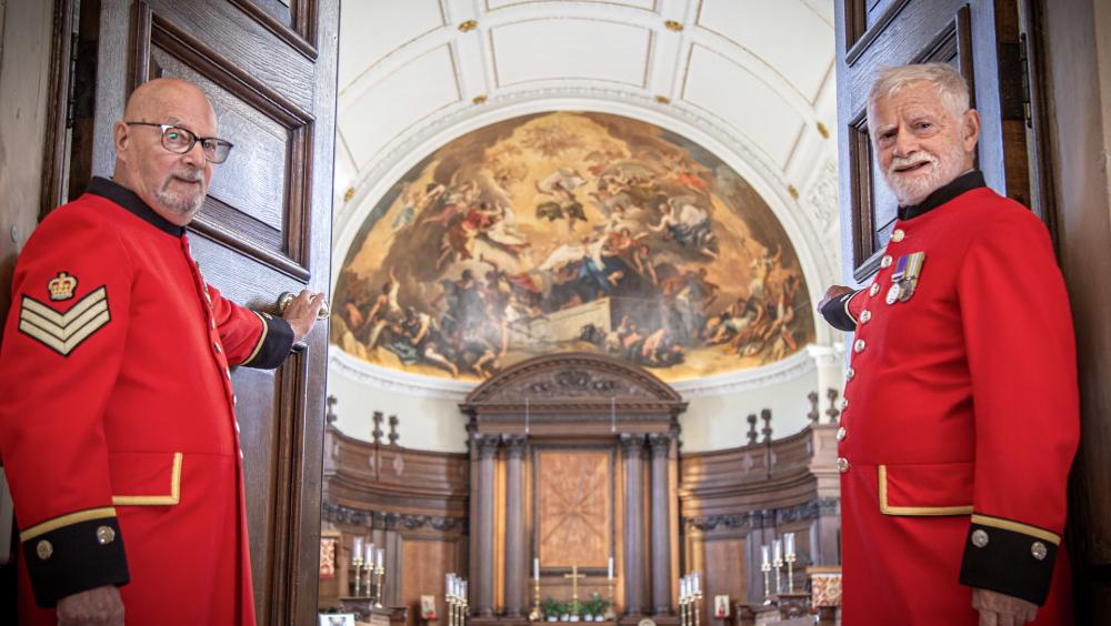 Two Chelsea Pensioners stand aside to welcome you as they open the doors of the Wren Chapel