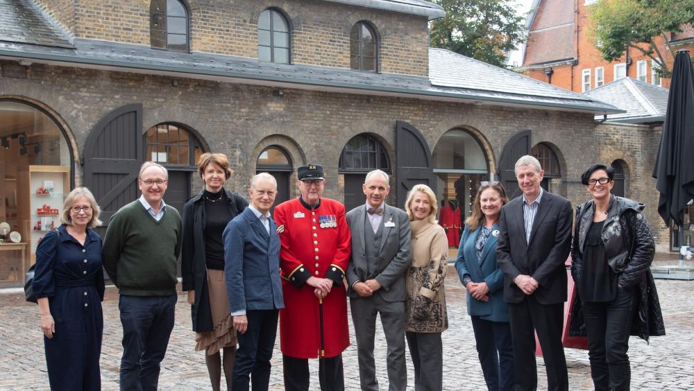 A group of visitors and stakeholders stand together in the newly refurbished Soane Stable Yard at The Royal Hospital Chelsea