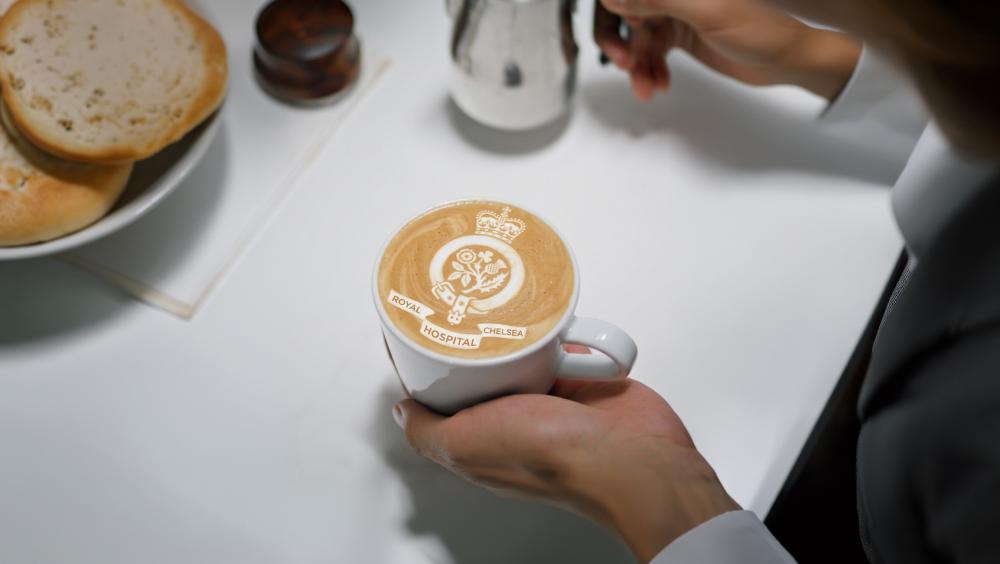 a coffee cup bearing the royal hospital chelsea logo in the foam