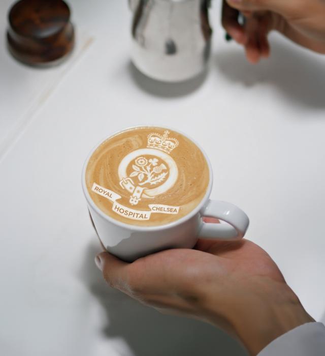 a coffee cup bearing the royal hospital chelsea logo in the foam