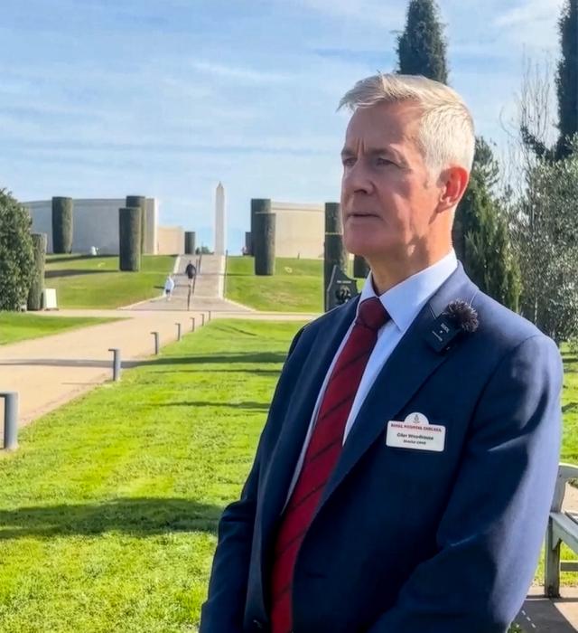 Giles Woodhouse, Director of the Chelsea Pensioners Veterans Outreach, stands outside under blue skies at the National Arboretum Memorial.