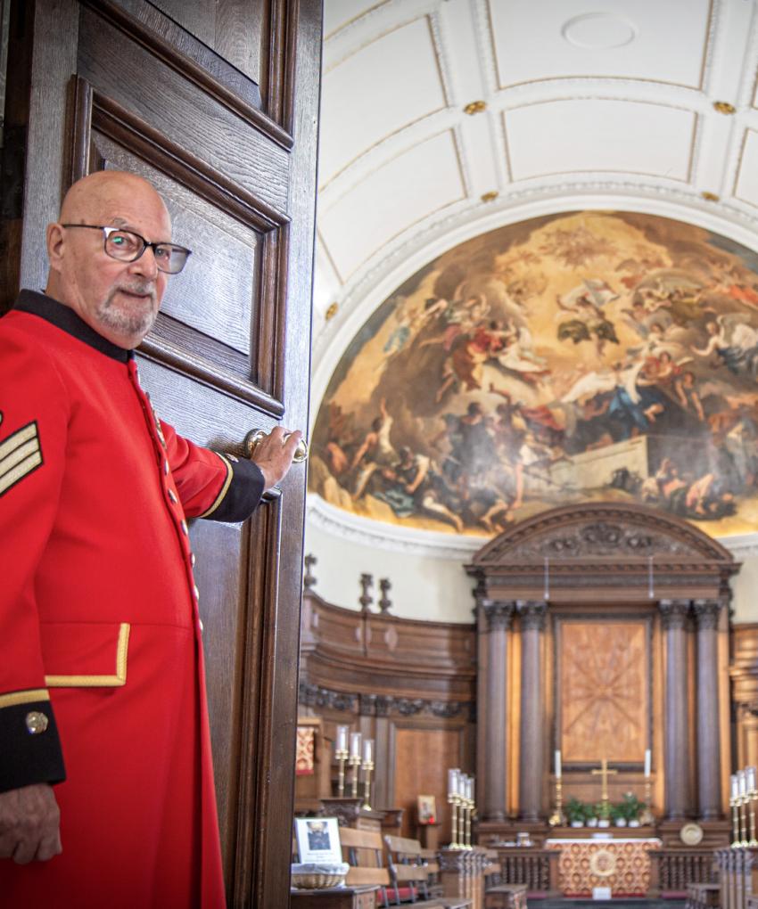 Two Chelsea Pensioners stand aside to welcome you as they open the doors of the Wren Chapel