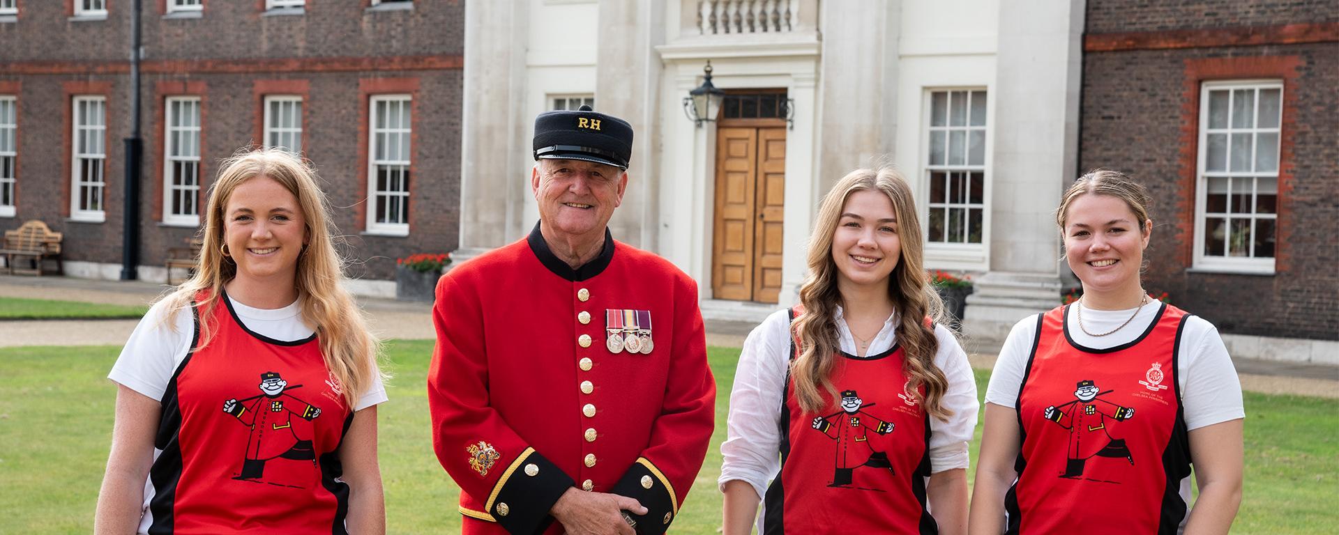 Fundraisers in Chelsea Pensioners running shirts stand alongside a Chelsea Pensioner in Figure Court at the Royal Hospital Chelsea