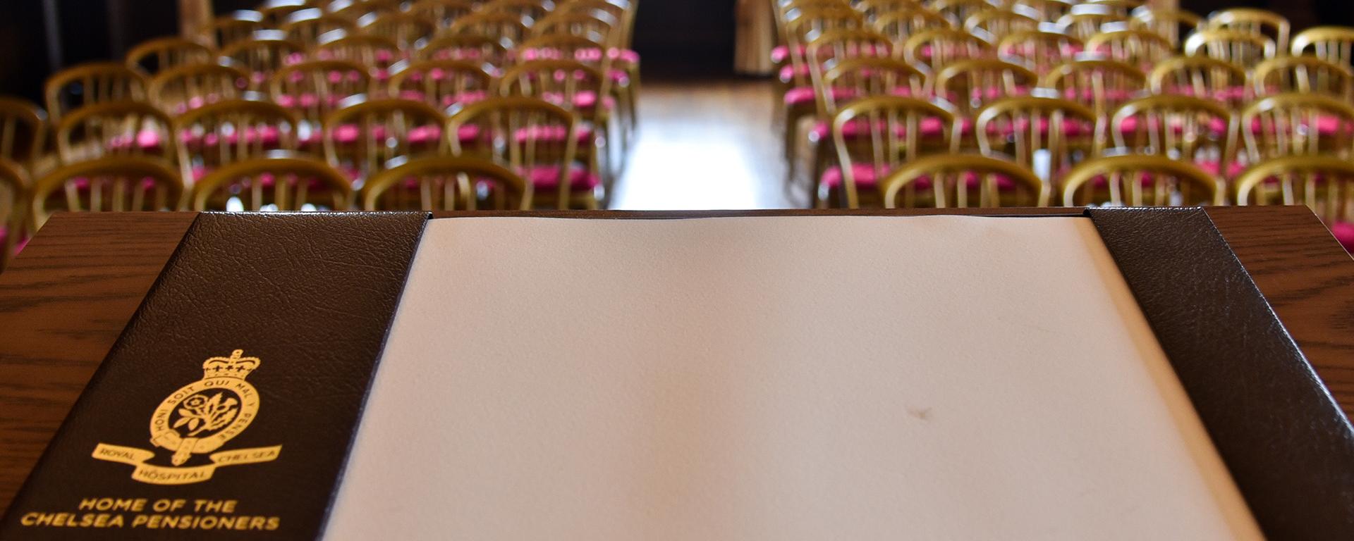 A Royal Hospital branded blotting pad sits on a lectern overlooking and empty conference meeting 
