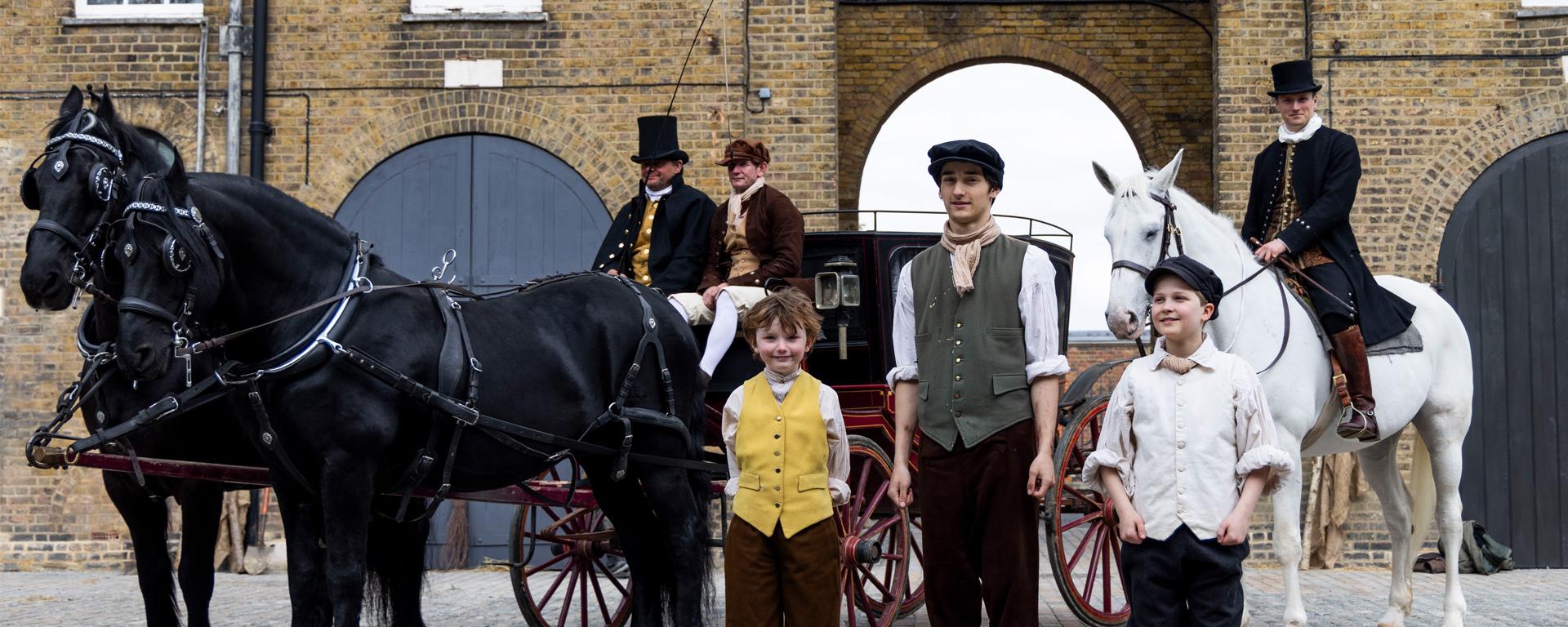 A group of costumed re-enactors stand together with a horse-drawn carriage at the newly renovated Soane Stable Yard