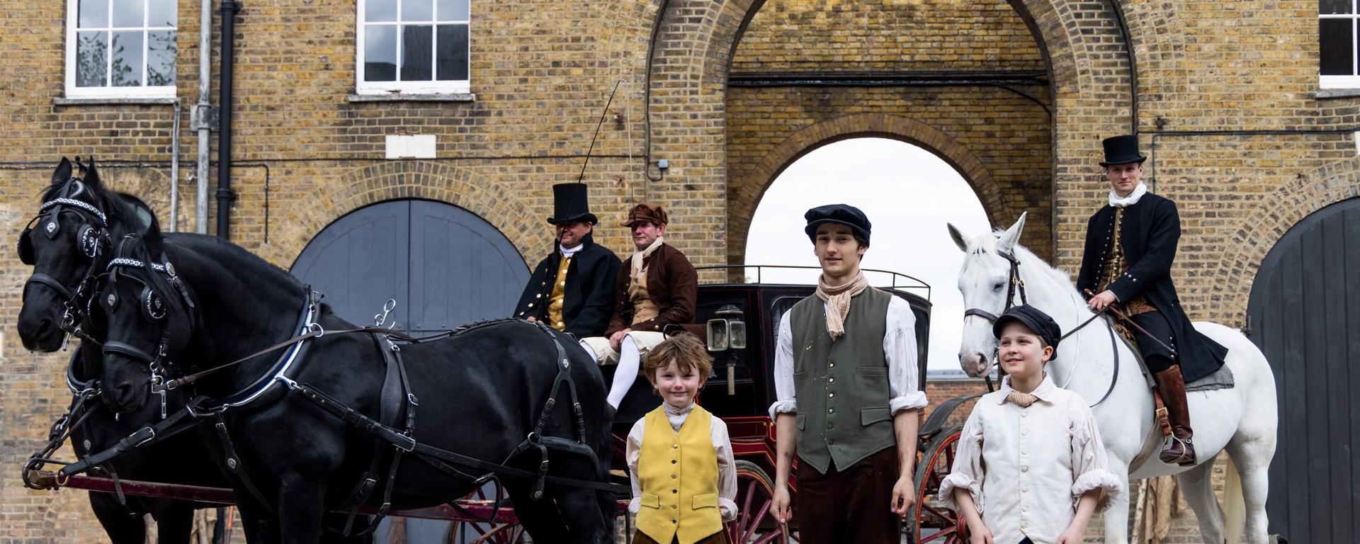 A group of costumed re-enactors stand together with a horse-drawn carriage at the newly renovated Soane Stable Yard