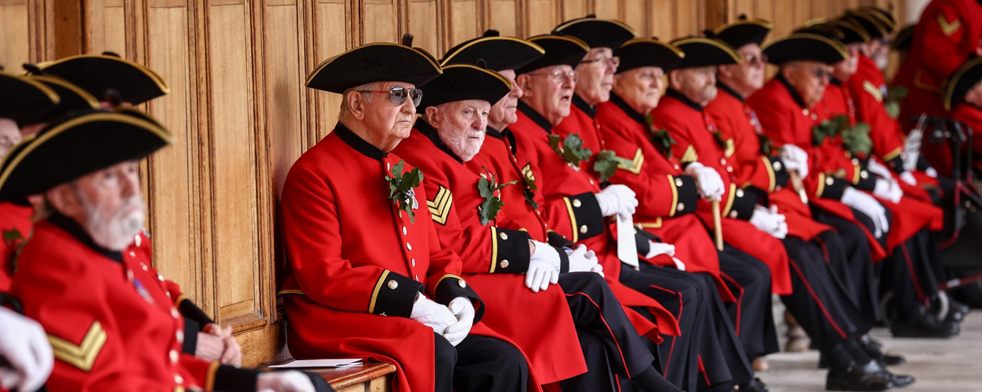 Chelsea Pensioners sitting along the colonnade in Figure Court during Founder's Day 2022.