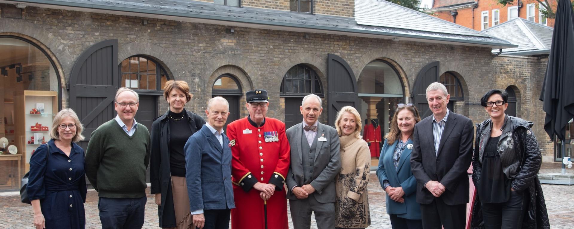 A group of visitors and stakeholders stand together in the newly refurbished Soane Stable Yard at The Royal Hospital Chelsea