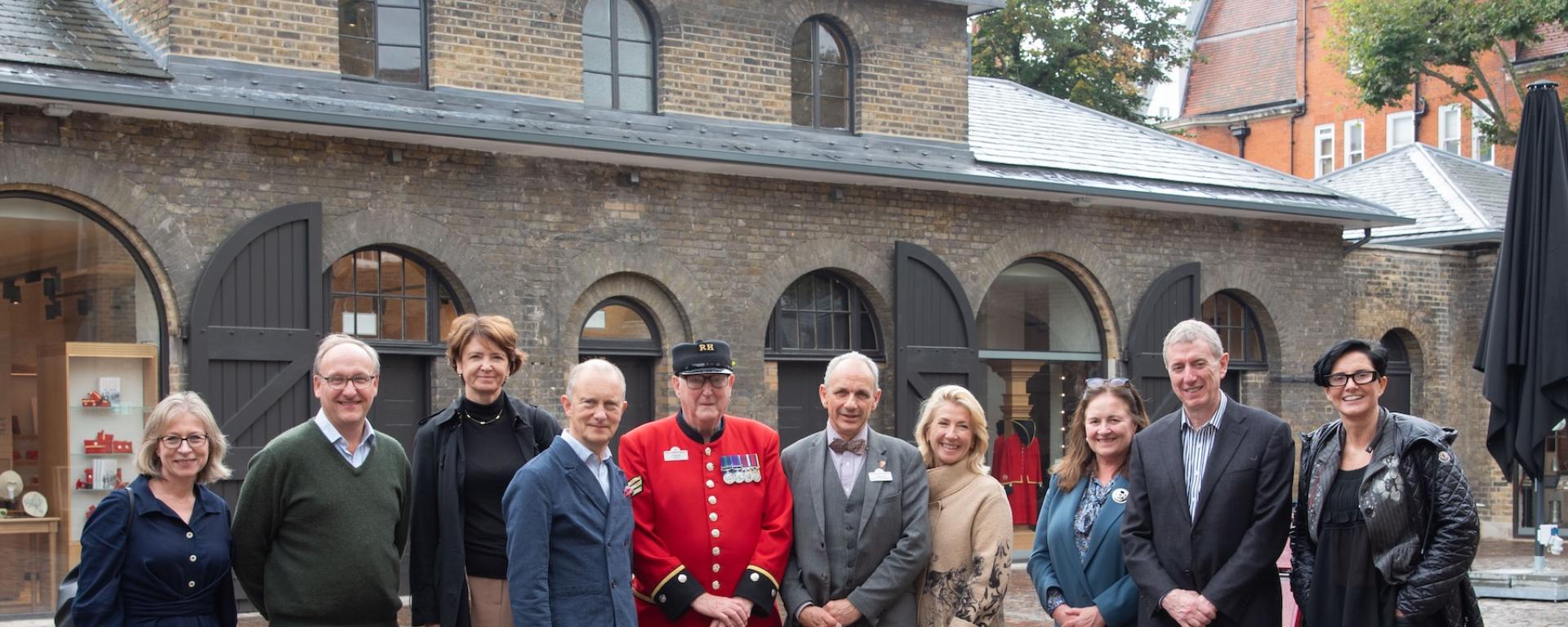 A group of visitors and stakeholders stand together in the newly refurbished Soane Stable Yard at The Royal Hospital Chelsea