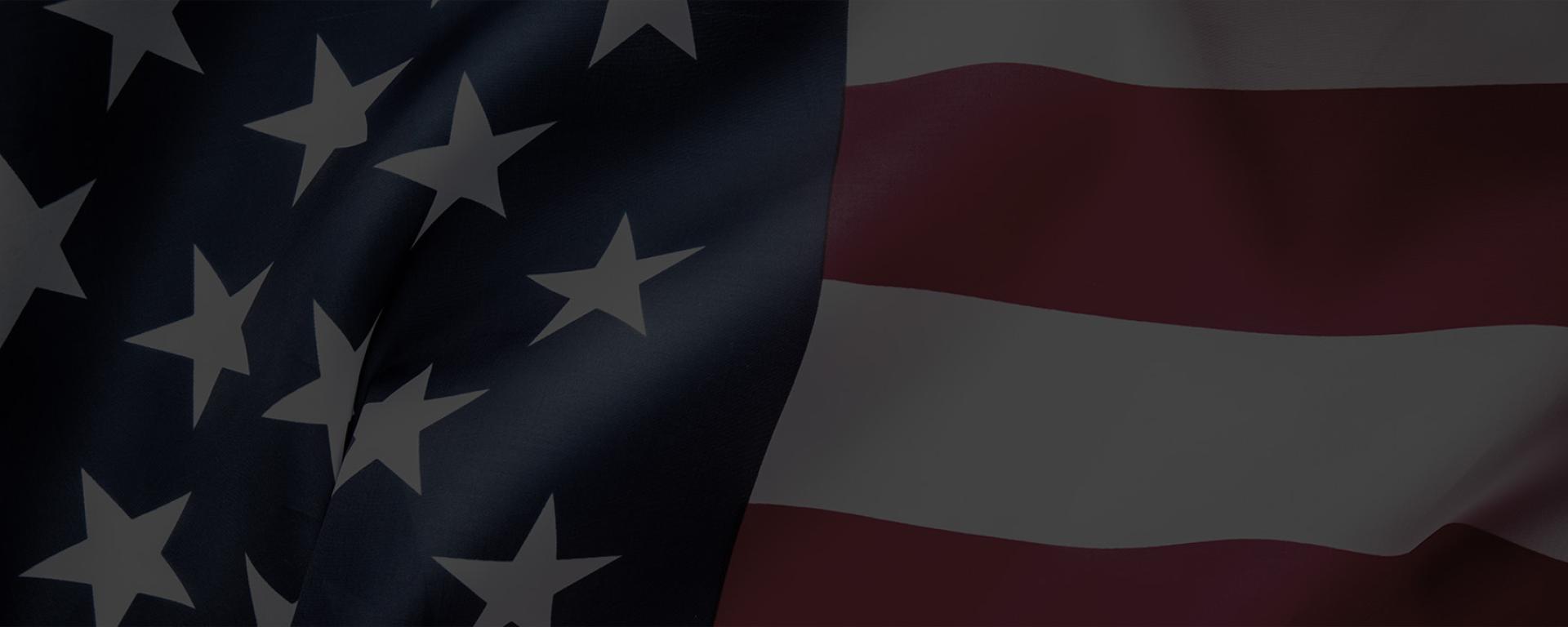 An American flag zoomed in revealing a crinkled Stars and Stripes banner blowing in the wind