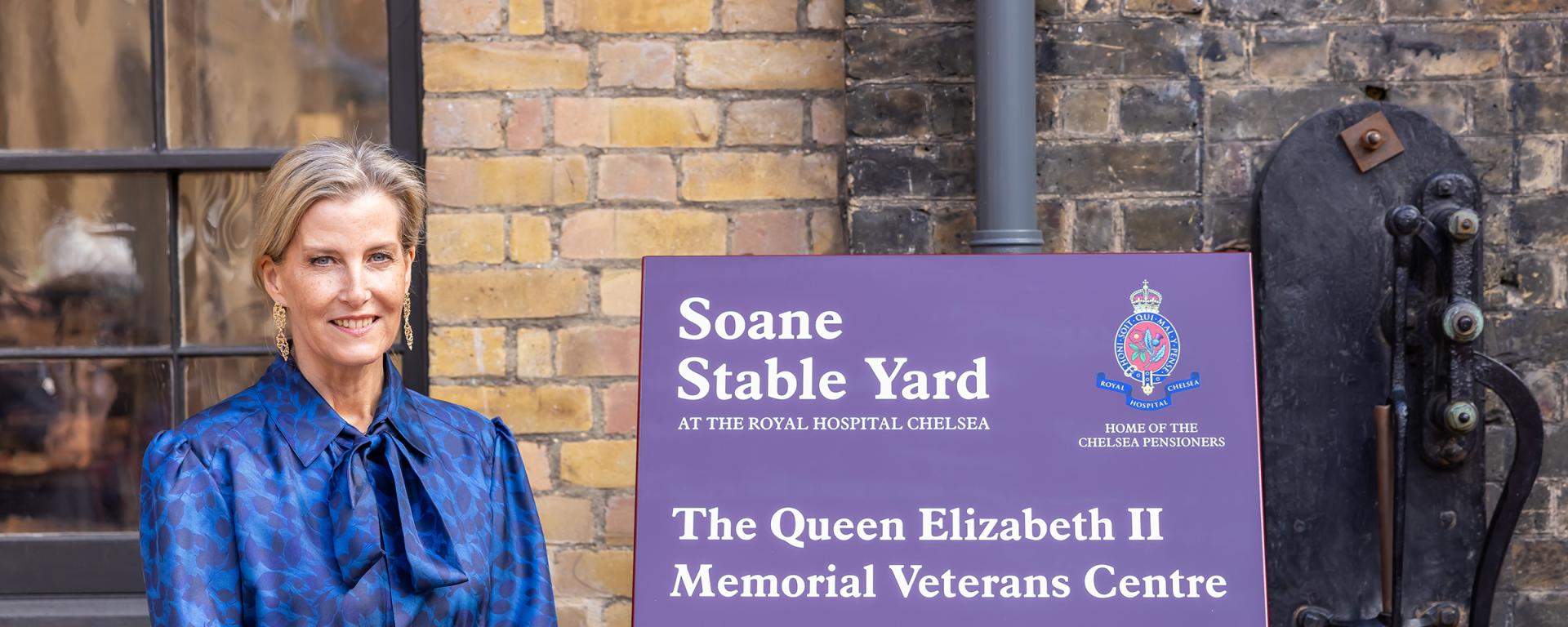  The Duchess of Edinburgh standing beside a sign for the Queen Elizabeth II Memorial Veterans Centre at the Soane Stable Yard, Royal Hospital Chelsea.