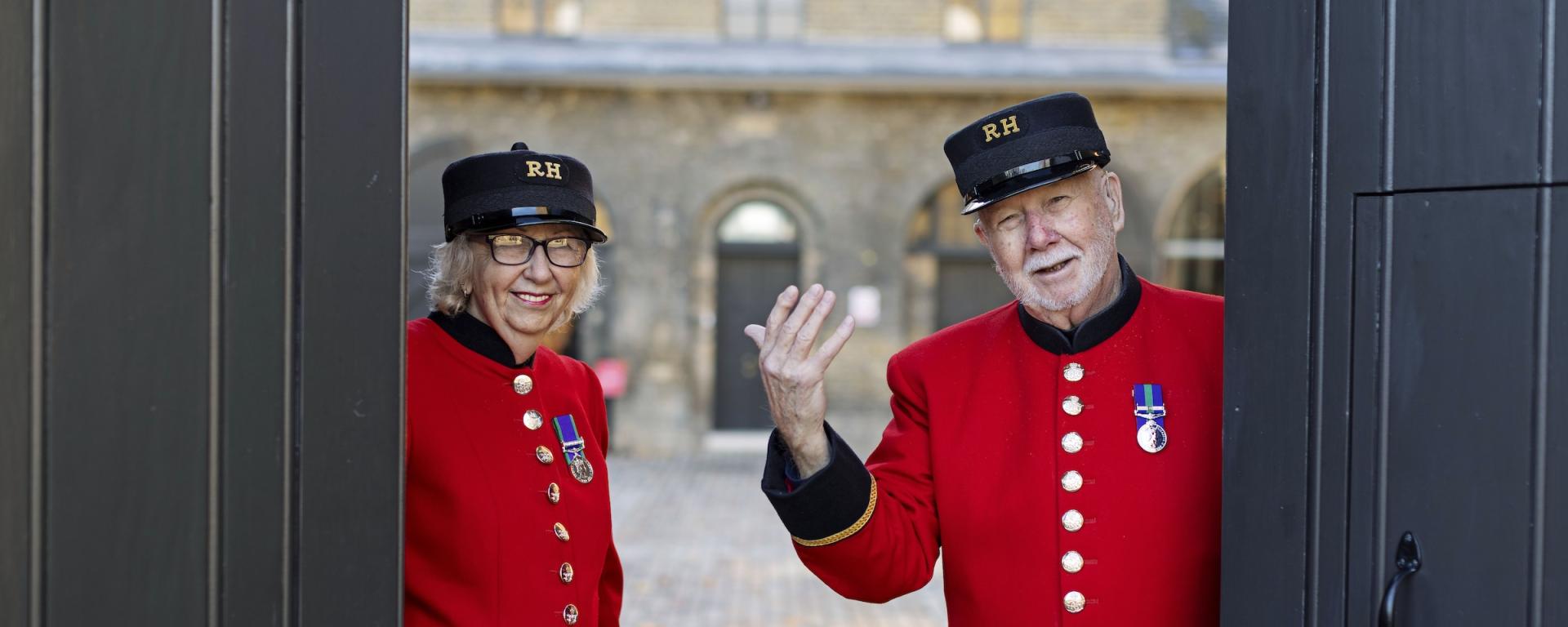 Two Chelsea Pensioners in scarlet uniforms welcome visitors through the entrance to the Soane Stable Yard at the Royal Hospital Chelsea.