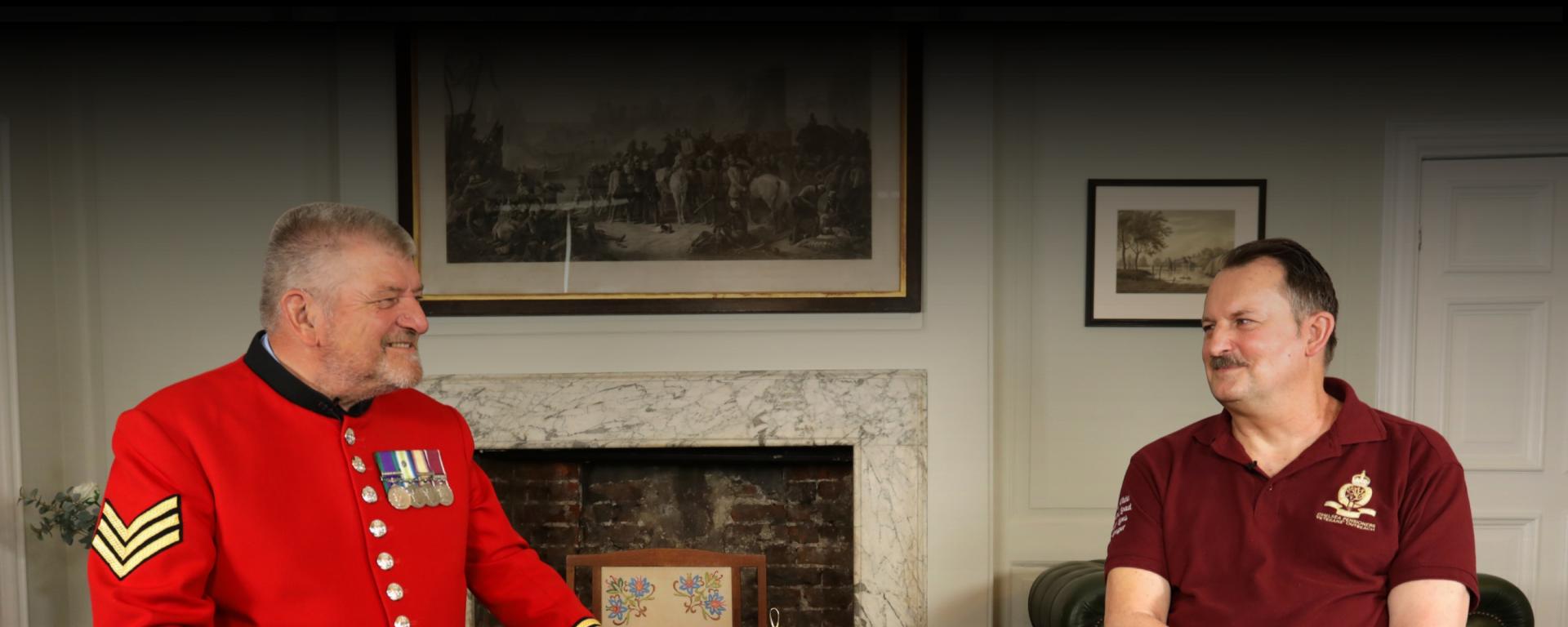 An image of Chelsea Pensioner Paul and Veterans Outreach member Mal, sitting on a black chair at the Royal Hospital Chelsea and having a conversation