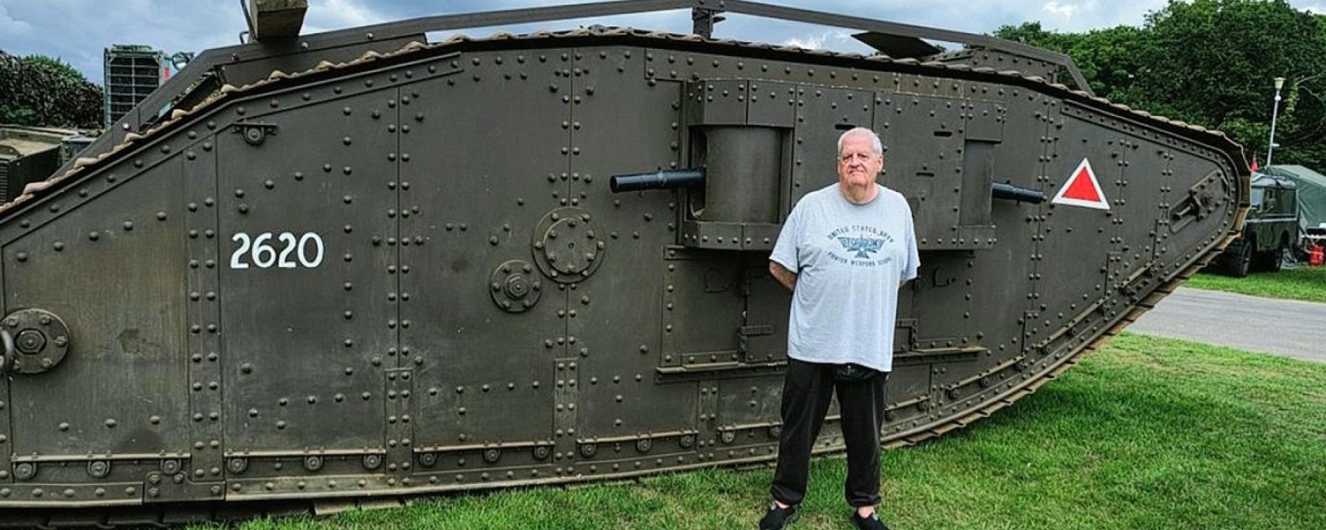 An image of military historian Paul Hunt standing in front of a tank in a green space, promoting the Hands-On History: World War One Artifacts event at Royal Hospital Chelsea.
