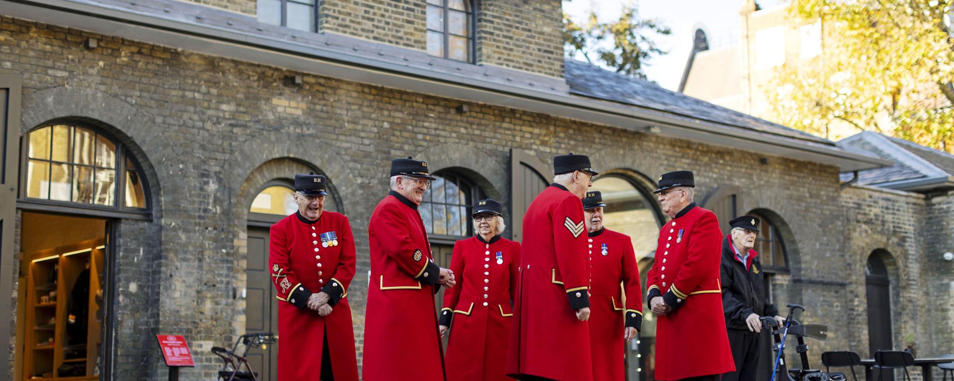 a Group of Chelsea Pensioners in their red uniforms standing outside of the Soane Stable Yard at Royal Hospital Chelsea