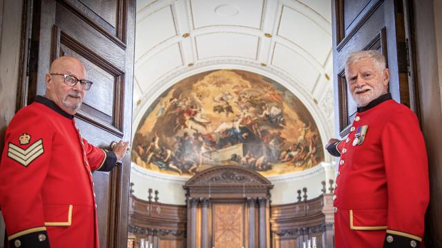 Two Chelsea Pensioners stand aside to welcome you as they open the doors of the Wren Chapel
