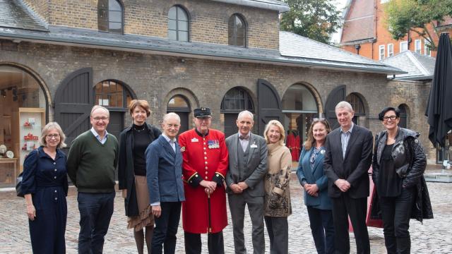 A group of visitors and stakeholders stand together in the newly refurbished Soane Stable Yard at The Royal Hospital Chelsea