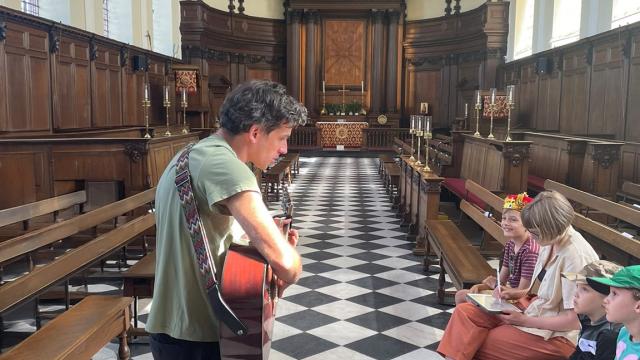 A musician plays his guitar for a family audience in the Wren Chapel at the Royal Hospital Chelsea