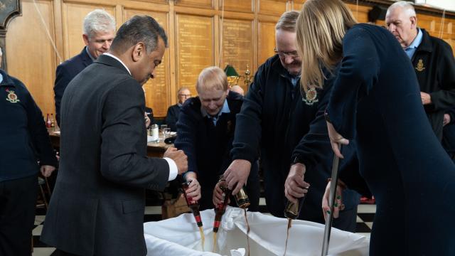 Chelsea Pensioners and staff adding ingredients to the Christmas pudding mixture