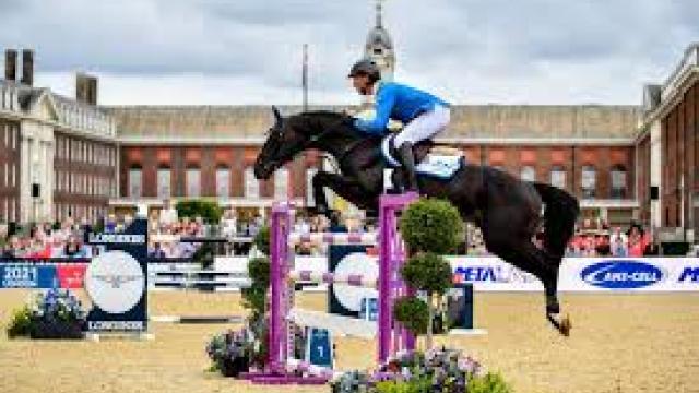 A rider mounted on a horse jumping during competition set amongst the backdrop of Royal Hospital Chelsea