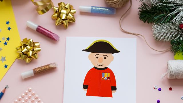 A colourful table adorned with craft making suppliers a Christmas Garlands. A Christmas card depicts a hand crafted Chelsea Pensioner
