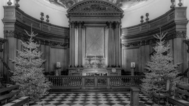 An old black and white photo of the alter at the Royal Hospital Chelsea's Wren Chapel - with Christmas trees on either side of the photo