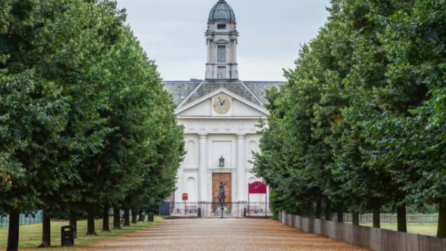Burton Court at Royal Hospital Chelsea. A path lined with tall green trees and a historical building in the background.