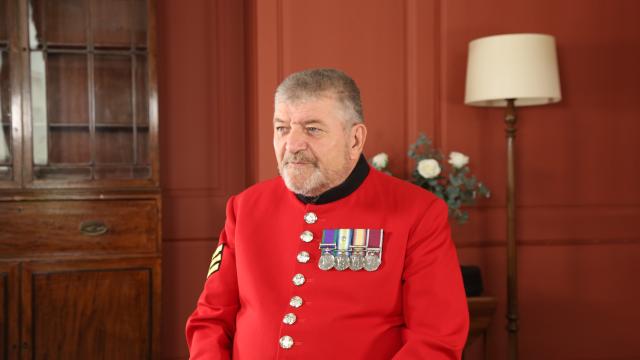 Chelsea Pensioner Paul Sinclair sitting on a chair in his red scarlet uniform